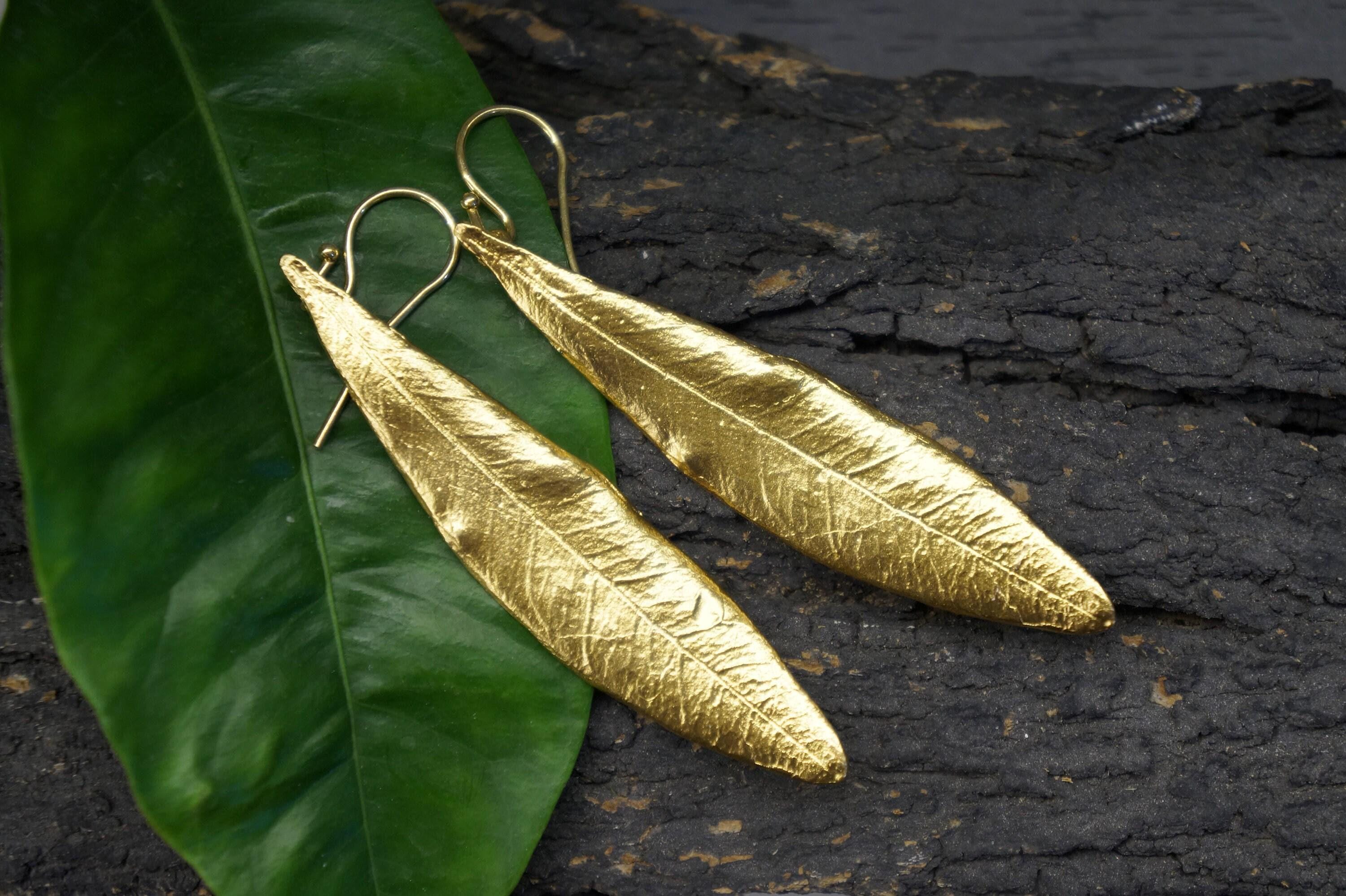 The Olive Leaf Dangle Earrings embody nature's elegance, inviting you to adorn yourself with a symbol of peace and beauty. Handcrafted with care, these exquisite pieces in gold or silver plating reflect the delicate artistry of real olive leaves. Embrace their unique charm as a meaningful addition to your collection or as a thoughtful gift for someone special. Each pair is a celebration of sustainability and individuality, perfect for those who seek to wear their intentions close to their heart.